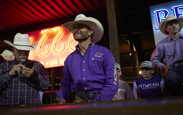 Dustin Boquet standing on the bucking chutes getting ready to ride.